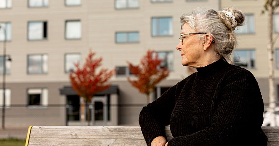 Godt voksen dame sitter på benk ute, til illustrasjon for SeniorLån
