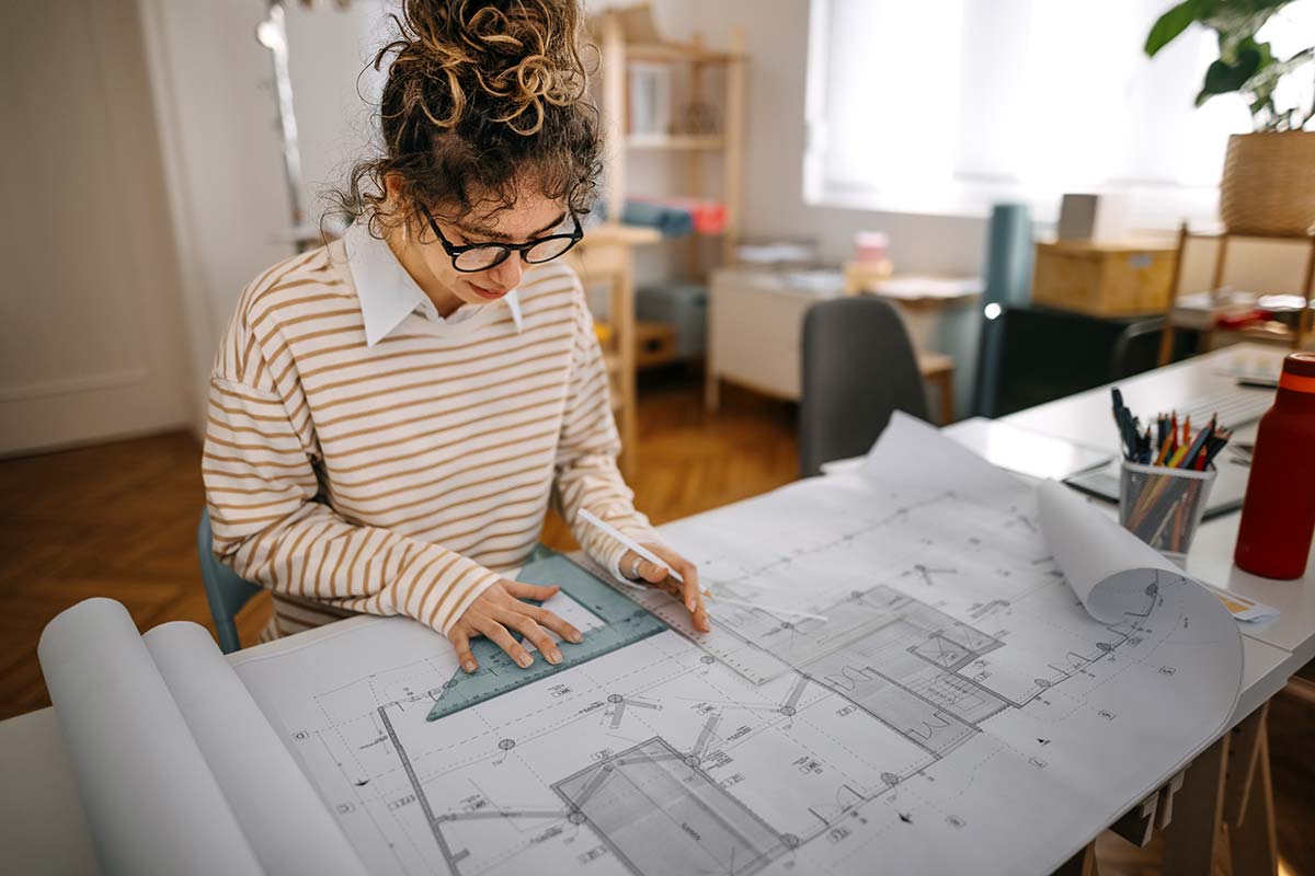 Arkitekt jobber med tegninger for noen som skal bygge på huset