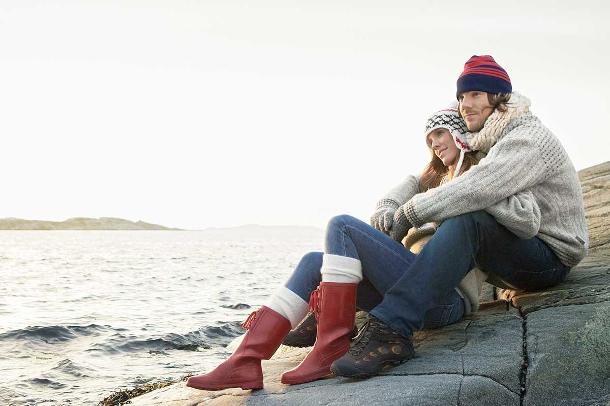 Kvinne lener seg mot mann på svaberg, til illustrasjon for skatt og samboere