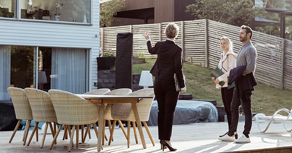 Megler på visning med et par viser fremsiden av en bolig og terrasse