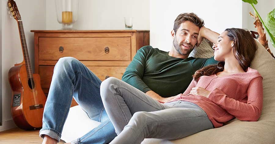 Bilde av et par som prater i sofaen, til illustrasjon av felles økonomi som gift, samboere eller romkamerater