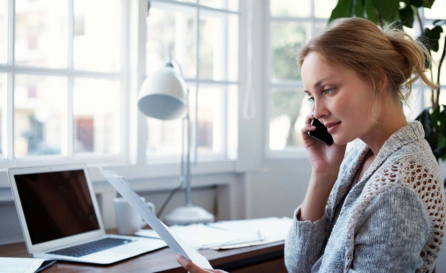 Kvinne snakker i telefonen mens hun holder et dokument, til illustrasjon for gjeldsordning