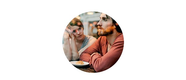 Kvinne lener seg på håndflaten og ser på en mann med skjegg, til illustrasjon for gjeld i parforhold