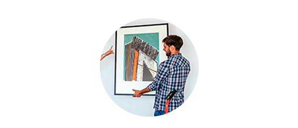 Mann henger opp bilde på vegg, til illustrasjon for kjøpe bolig