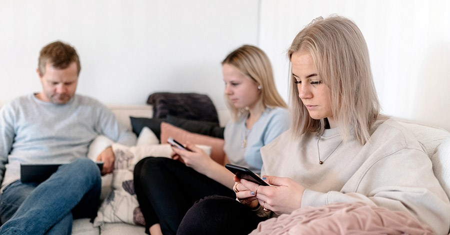 Bilde av to jenter i sofaen på hver sin telefon, til illustrasjon av unge voksne som får nyttige tips til voksenlivet på BN Bank.