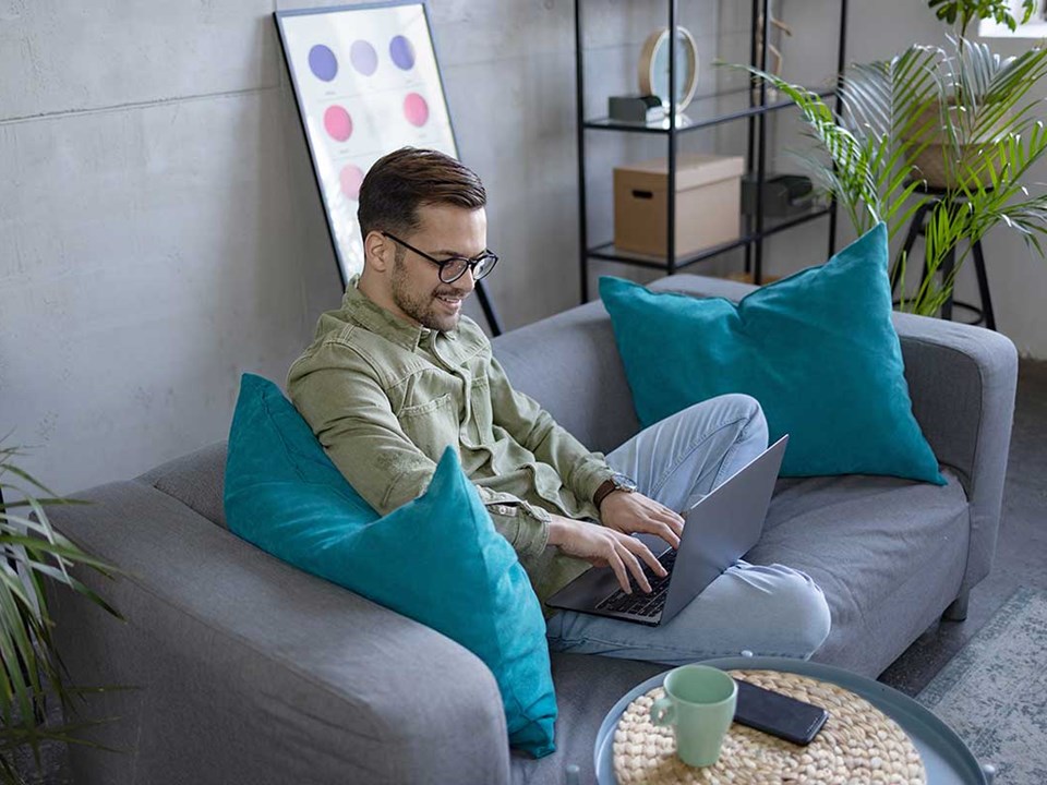Mann sitter i sofa og setter opp budsjett