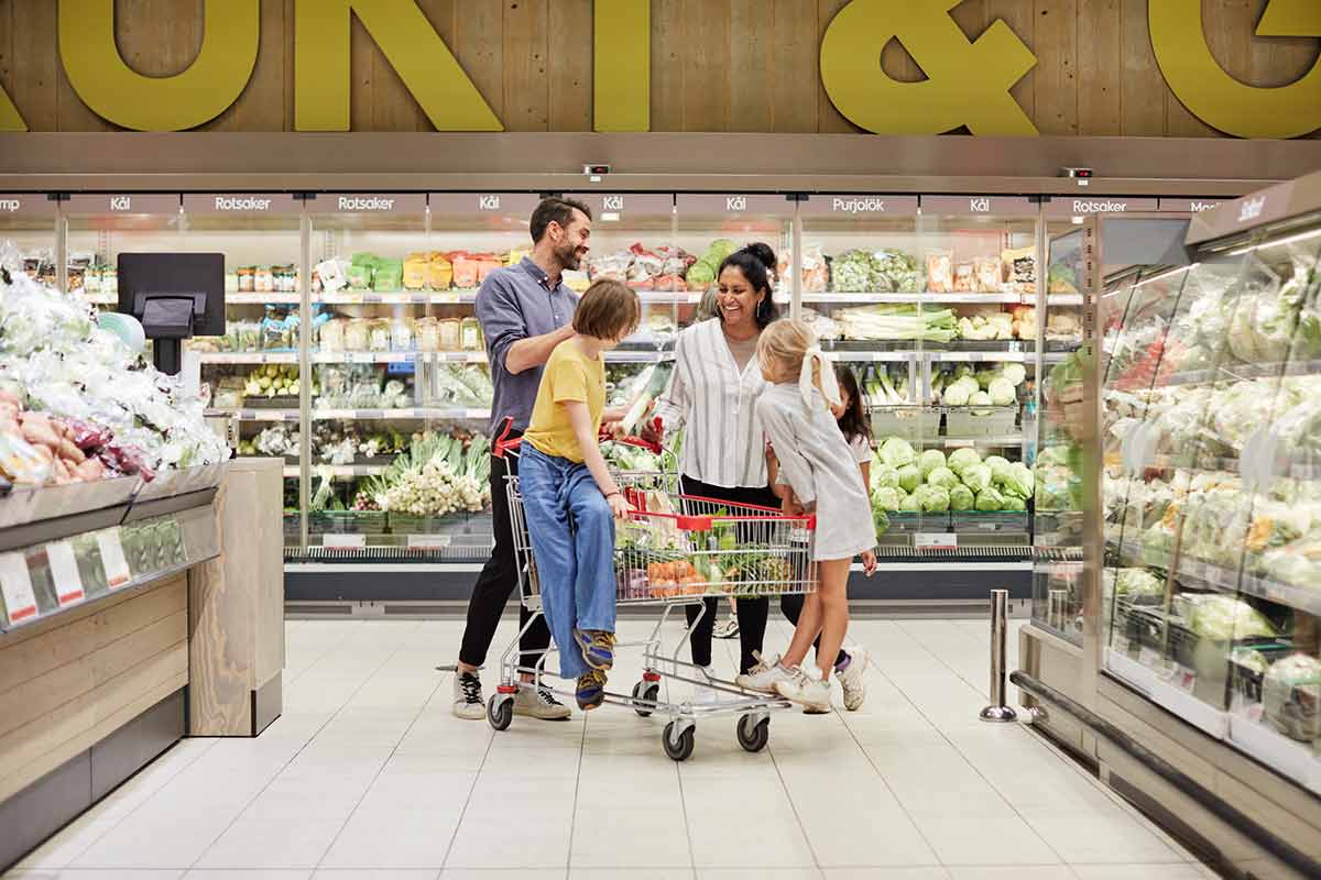 Mann, kvinne og to barn i en matbutikk, til illustrasjon for hvordan spare penger i hverdagen