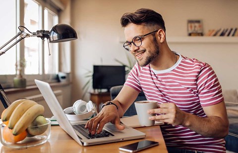 Mann drikker kaffe og ser på pc, illustrasjon til boligsparing