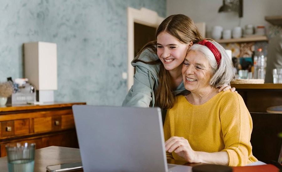 Jente klemmer eldre kvinne mens de ser på en dataskjerm, til illustrasjon for spare til barnebarn