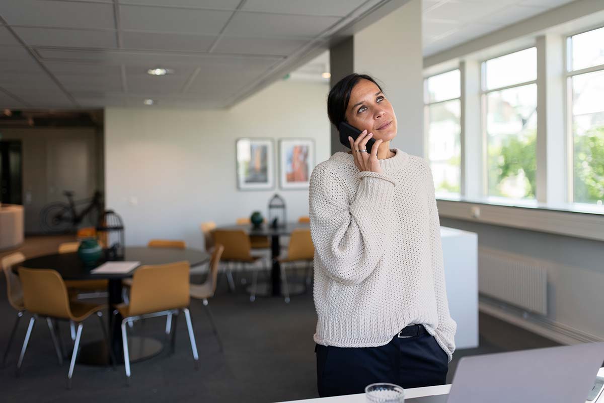 Dame står i et kontorlandskap og snakker i telefonen, til illustrasjon for NIBOR-konto