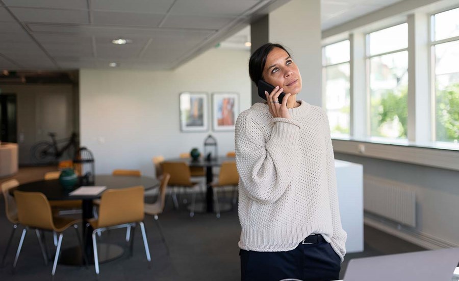 Dame står i et kontorlandskap og snakker i telefonen, til illustrasjon for NIBOR-konto
