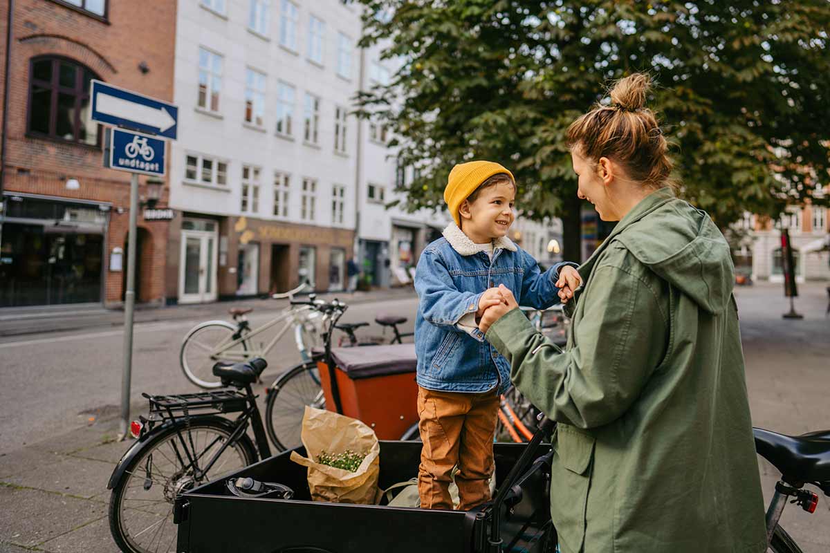 Mor og sønn holder hender mens gutten står på sykkelen, til illustrasjon for spareavtale