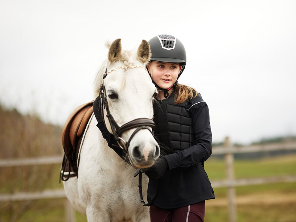 Barn sitter i fanget til mor og holder en sparegris, til illustrasjon for spare til barna