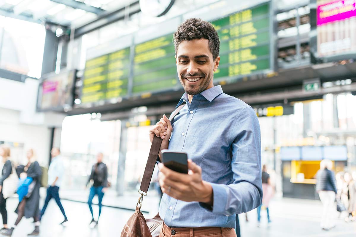 Mann på flyplass ser på mobiltelefonen, illustrasjon til mobilbank bedrift