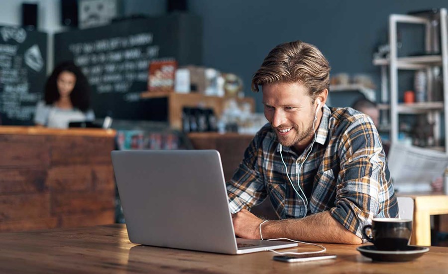 Mann med laptop på cafe