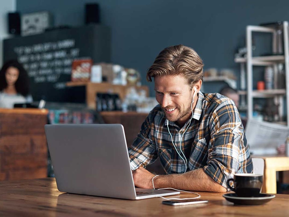 Mann med laptop på cafe
