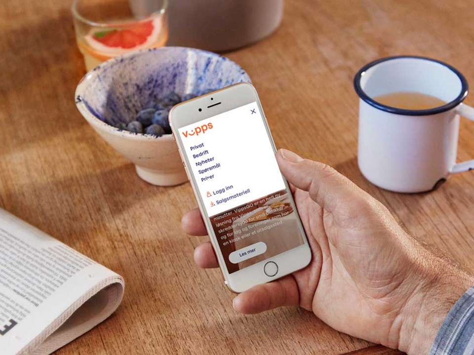 Mann holder en mobil som viser Vipps bedrift