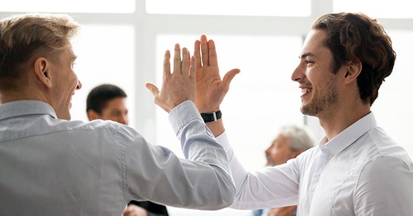 To menn gir hverandre en high five på kontoret, til illustrasjon for plasseringskonto