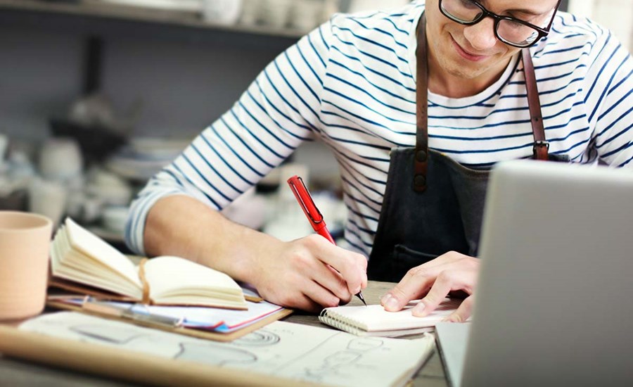 En mann med briller jobber på en laptop, fokusert på arbeid relatert til skattetrekkskonto