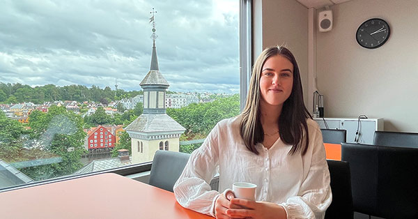 HR-rådgiver Emilie sitter på kantina i BN Bank med en kaffekopp, til illustrasjon for internship