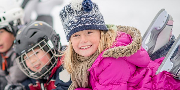 Barn leker ute i snøen og smiler, til illustrasjon for vinterferie