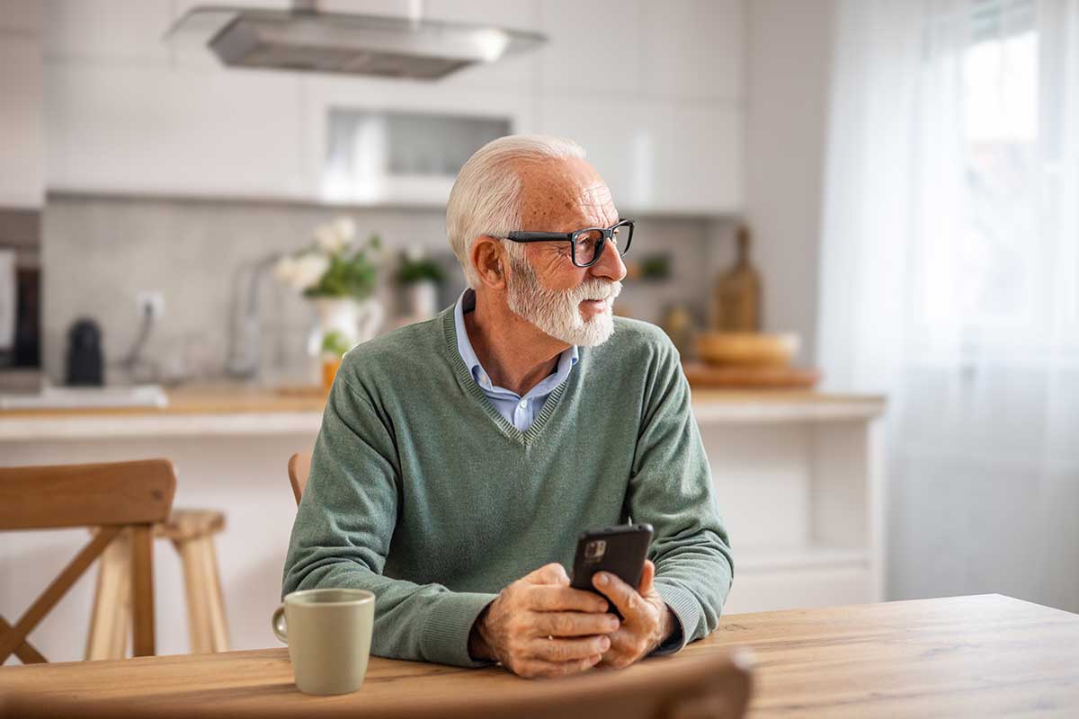 Mann sitter ved kjøkkenbordet med mobilen, illustrasjon for informasjon om dødsfaøø