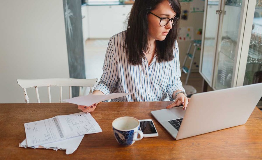 Dame sitter oag holder briller med en PC fremfor seg, til illustrasjon for klage